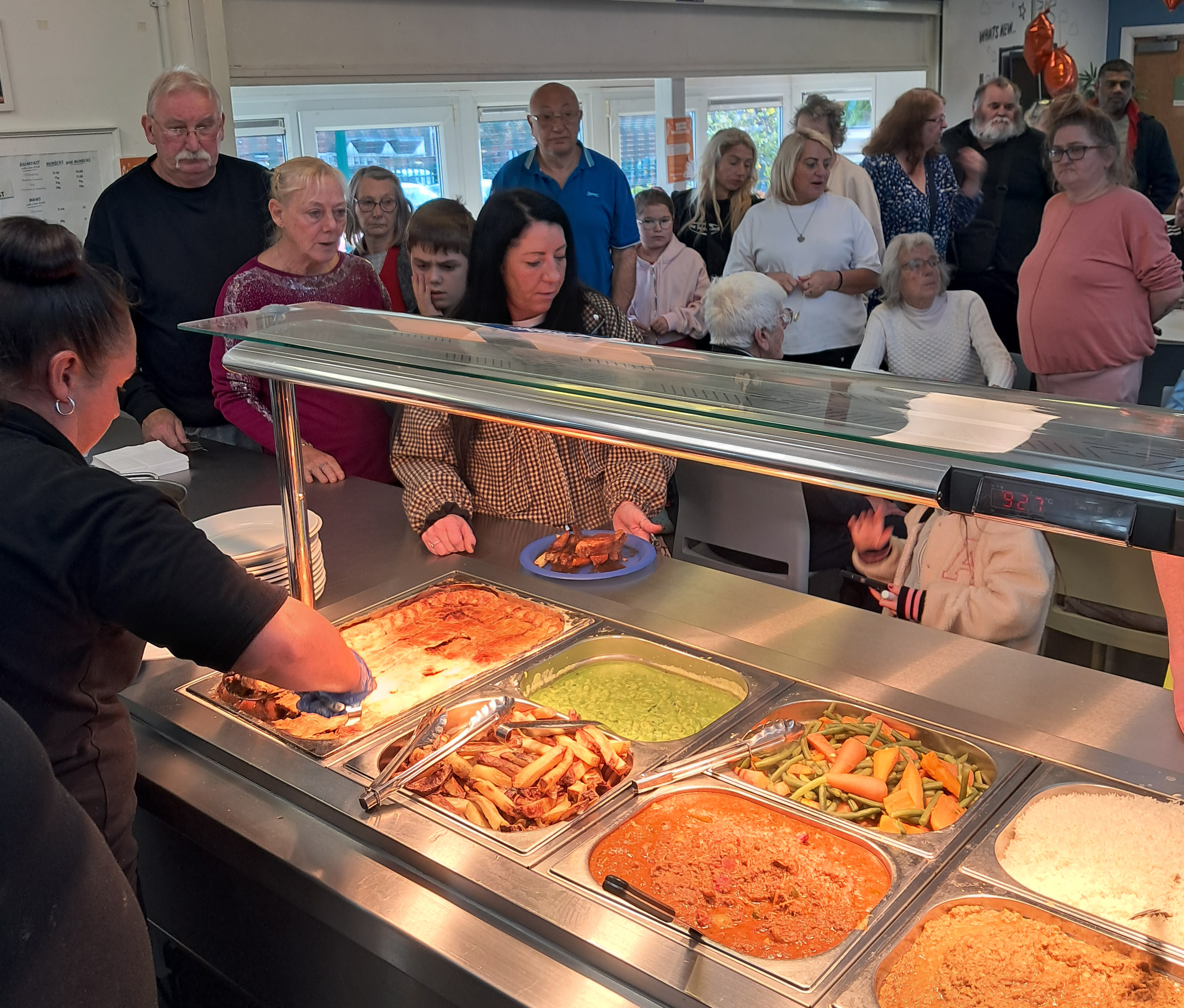 Community kitchen staff serve pie, peas, curry and vegetables to members of the Athersley Community.