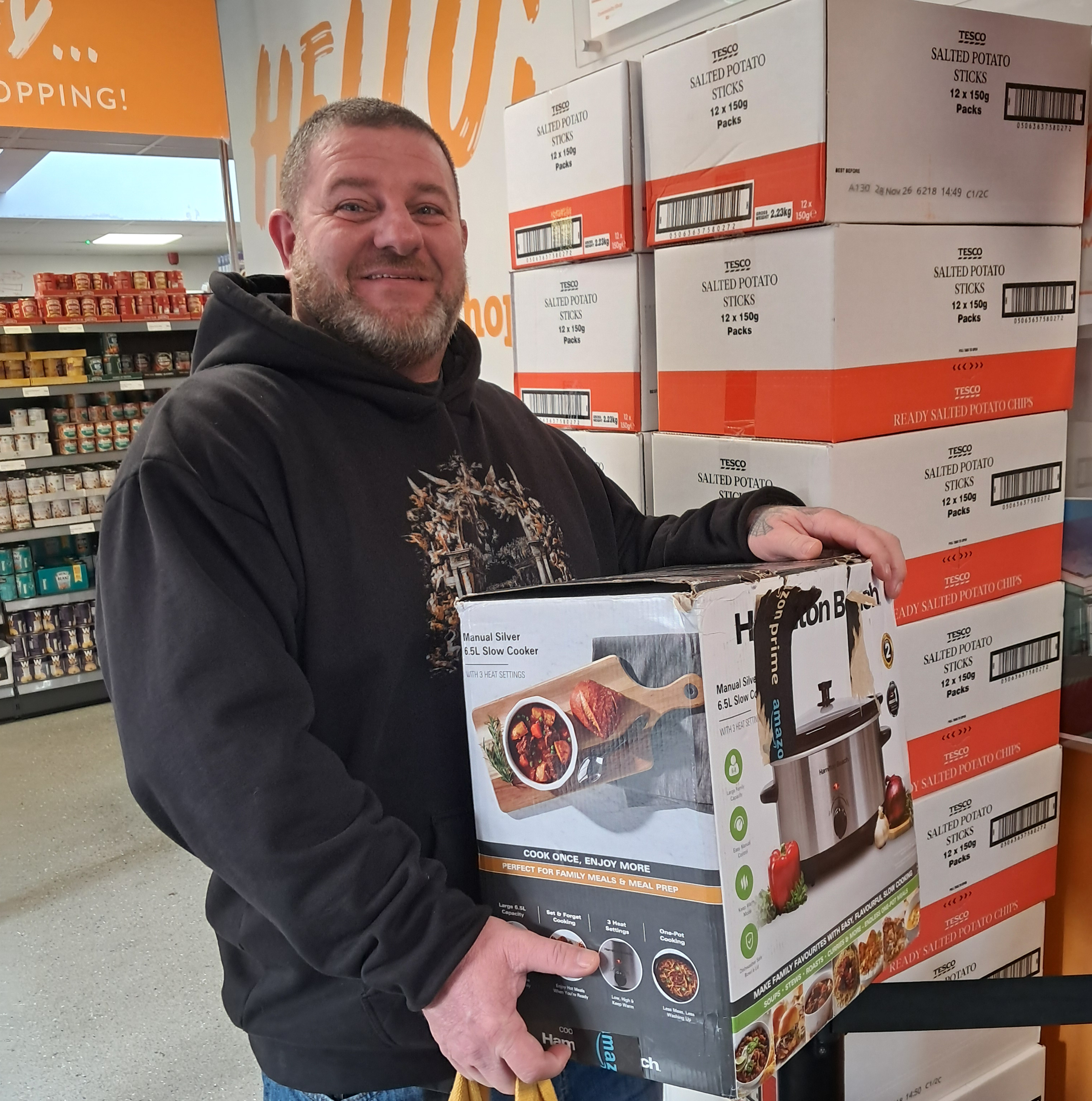 A man stands proudly with his slow cooker raffle prize.