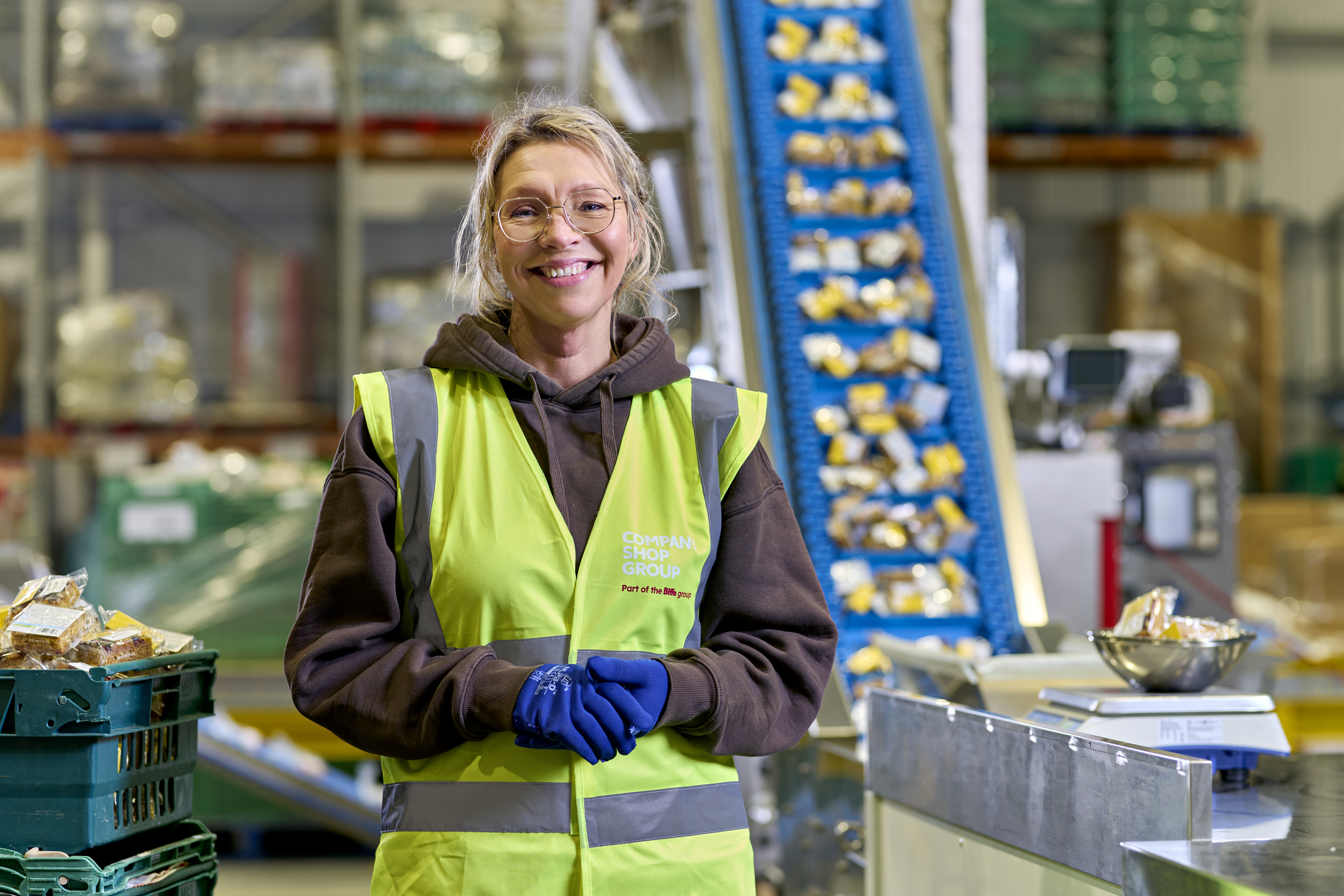 Smiling Company Shop Group employee wearing a high vis jacket in a warehouse