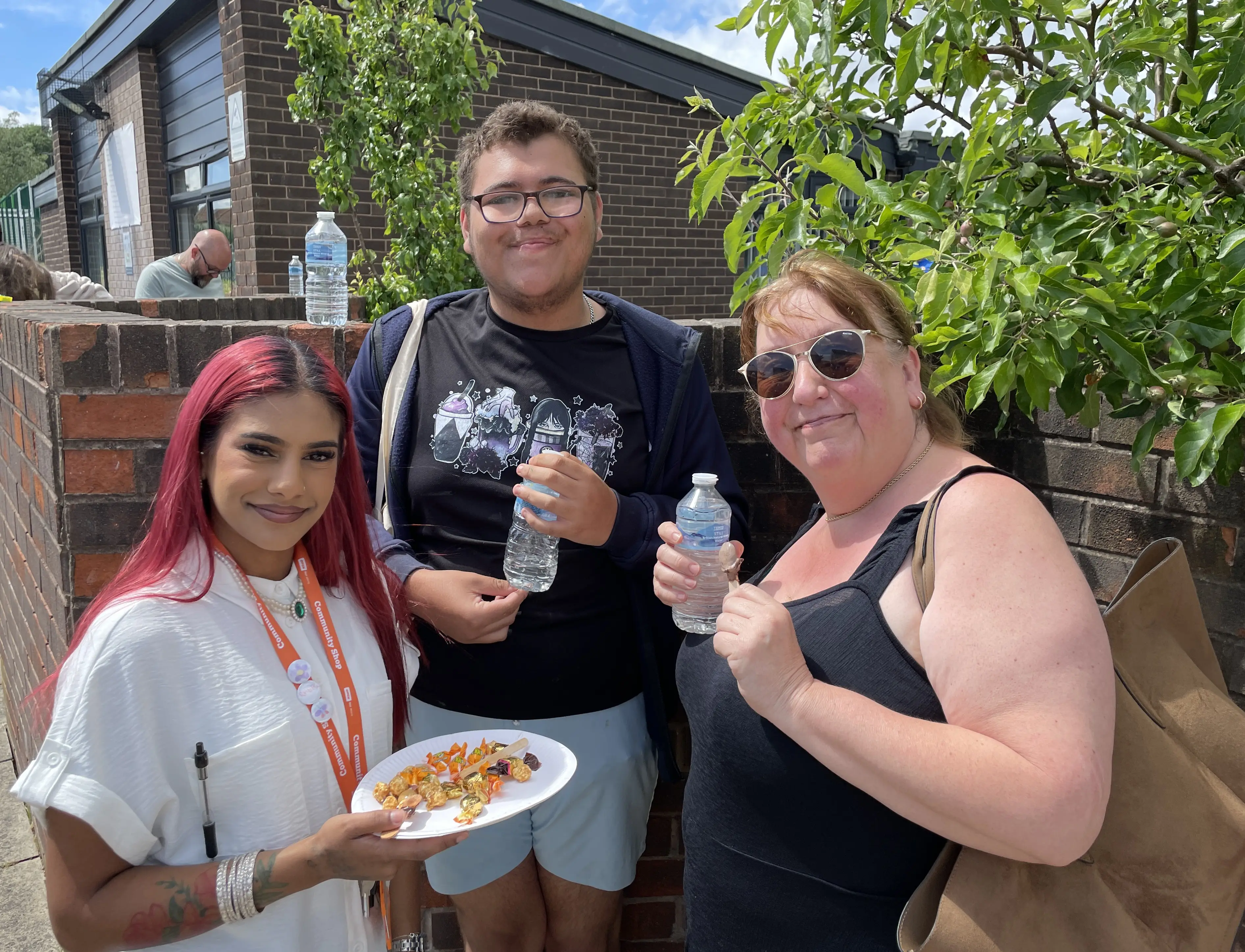 A family with paper plates of food smile at Community Shop Swarcliffe.