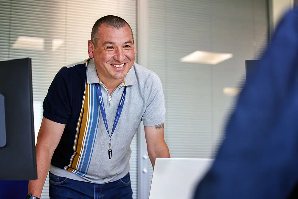 Member of the Company Shop Group partnerships team smiles as he welcomes a stock partner to a meeting.